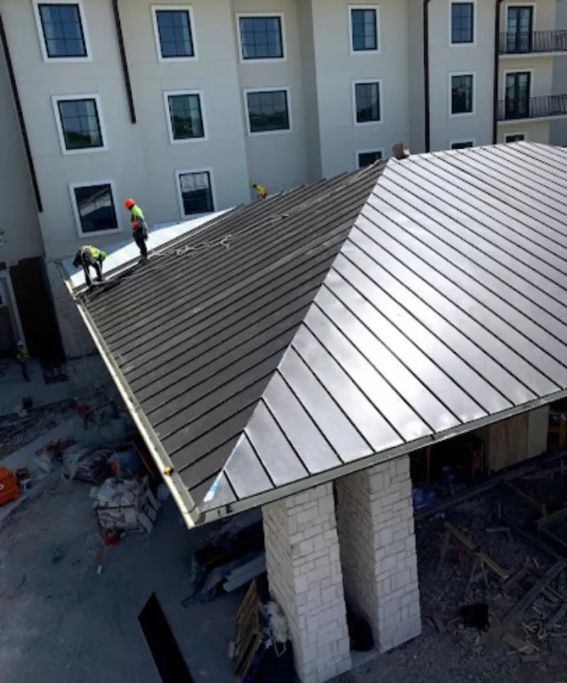 Crew installing standing seam metal roof panels on a commercial project in Dartmouth